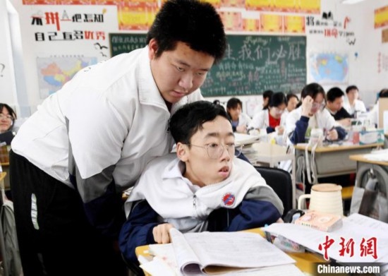 朱金祥(左)把鐘華強放到課堂座位上后，都要把他擺正好，確認安全后才回到自己的座位上。 卓忠偉 攝