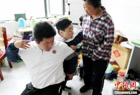 江西省南康中學北校區(qū)的高三學生朱金祥(左)來到學校給鐘華強母子安排的公寓，準備背他去課堂上課。 卓忠偉 攝
