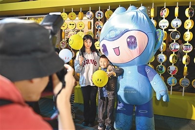 5月7日，在浙江省杭州市湖濱步行街“3D笑臉墻”前，攝影師為游客與杭州亞運(yùn)會吉祥物之一“宸宸”拍攝合影。