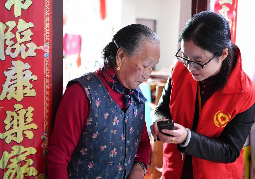 在福州市長(zhǎng)樂(lè)區(qū)航城街道籌岐村，智慧養(yǎng)老平臺(tái)派駐社區(qū)的助老員（右）在為老人陳鳳英（左）講解養(yǎng)老定制手機(jī)的用法（2021年11月26日攝）。新華社記者 魏培全 攝
