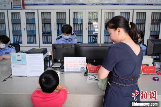 圖為一名家長正在辦證窗口前為孩子申領居民身份證。劉俊聰 攝