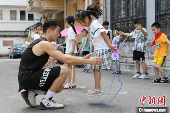 圖為大學(xué)生志愿者在教孩子們學(xué)跳繩。廖光福 攝