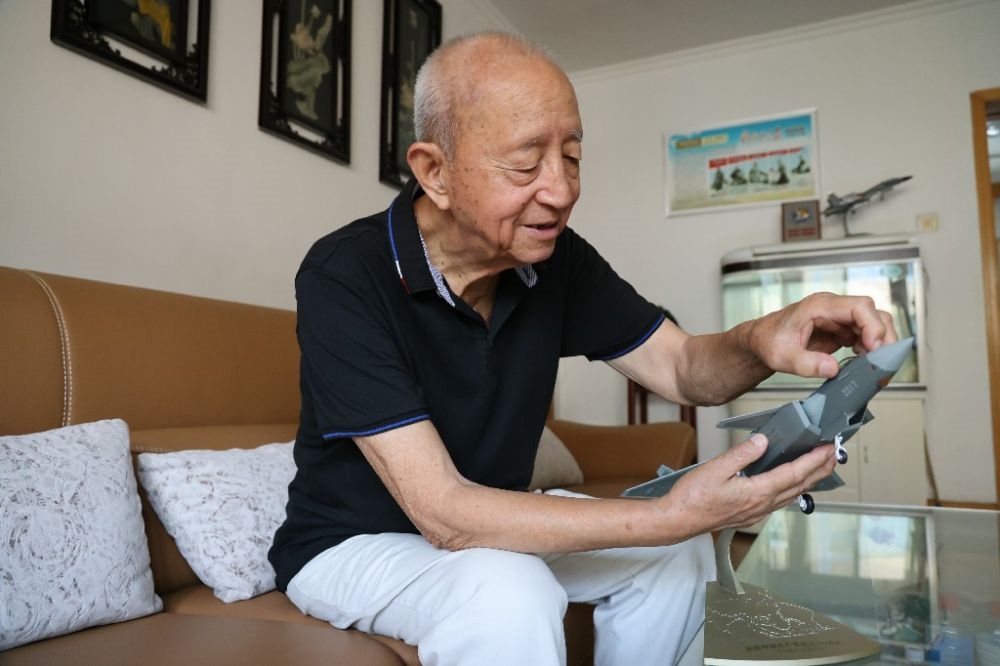 ↑2023年7月24日，新中國(guó)第一代飛行員陶偉在家中擦拭殲-20飛機(jī)模型。新華社發(fā)（張瑞 攝）