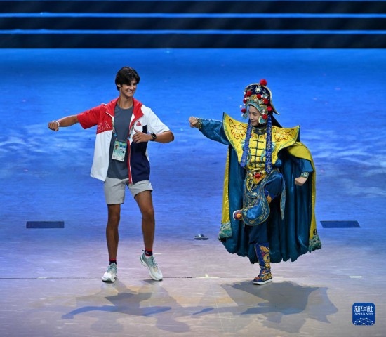 7月29日，美國運(yùn)動員杜恩（左）在聯(lián)歡會現(xiàn)場與川劇演員互動。新華社記者 蔡湘鑫 攝