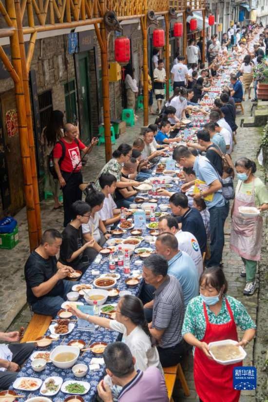 7月29日，在重慶市綦江區(qū)安穩(wěn)鎮(zhèn)，人們在“苗家伏羊節(jié)”上吃長桌宴。新華社記者 唐奕 攝