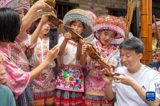 7月29日，在重慶市綦江區(qū)安穩(wěn)鎮(zhèn)，當?shù)鼐用裨凇懊缂曳蚬?jié)”上用傳統(tǒng)習俗向游客表達祝福。新華社記者 唐奕 攝
