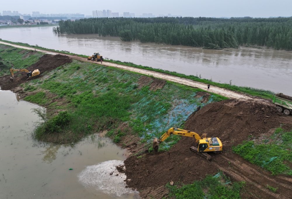 工人操作機(jī)械在白溝河左堤白溝新城高橋村段進(jìn)行除險(xiǎn)加固作業(yè)（8月4日攝，無人機(jī)照片）。新華社記者 朱旭東 攝