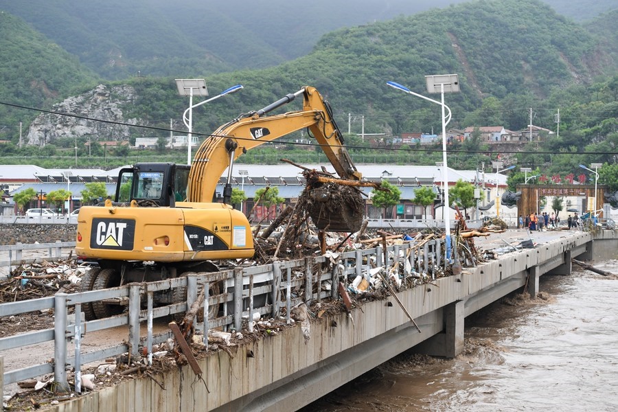 8月1日，在北京市門頭溝區(qū)水峪嘴村村口，一臺(tái)挖掘機(jī)在清理阻斷橋梁交通的雜物。目前該條道路已經(jīng)疏通完成。新華社記者 鞠煥宗 攝