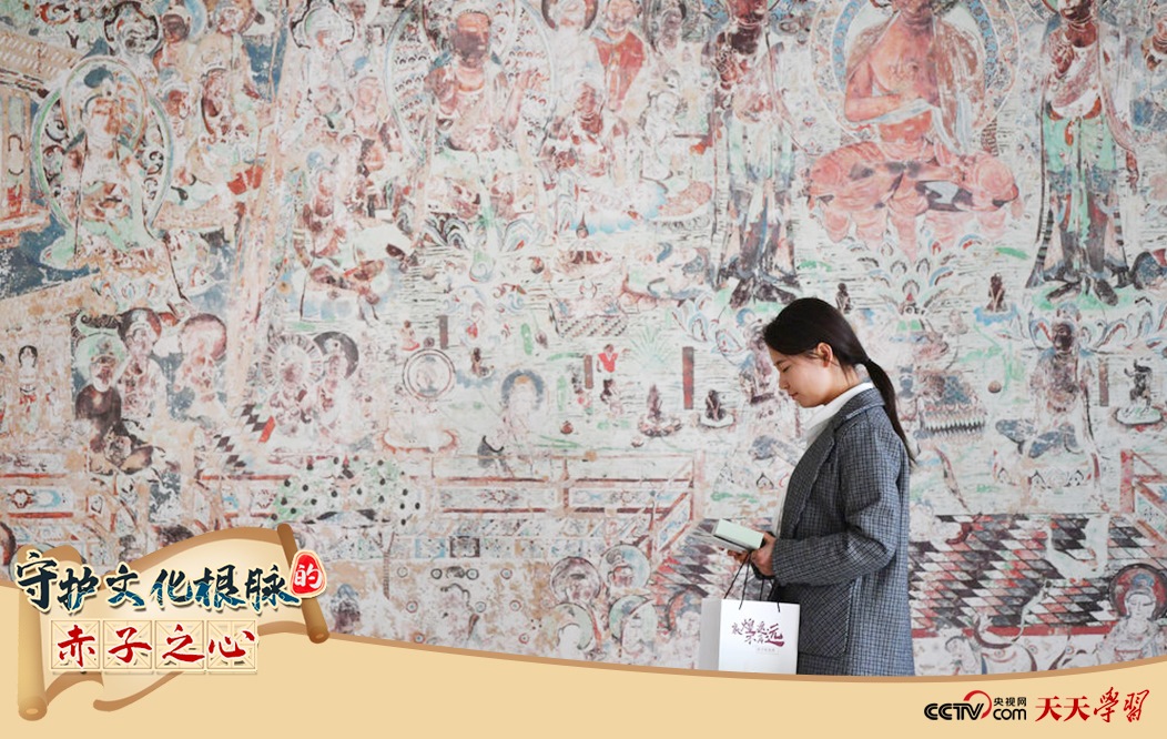 2023年4月25日，敦煌研究院文物數(shù)字化保護(hù)團(tuán)隊(duì)創(chuàng)意營(yíng)銷人員廖雪婷從一幅高保真復(fù)制壁畫前走過。