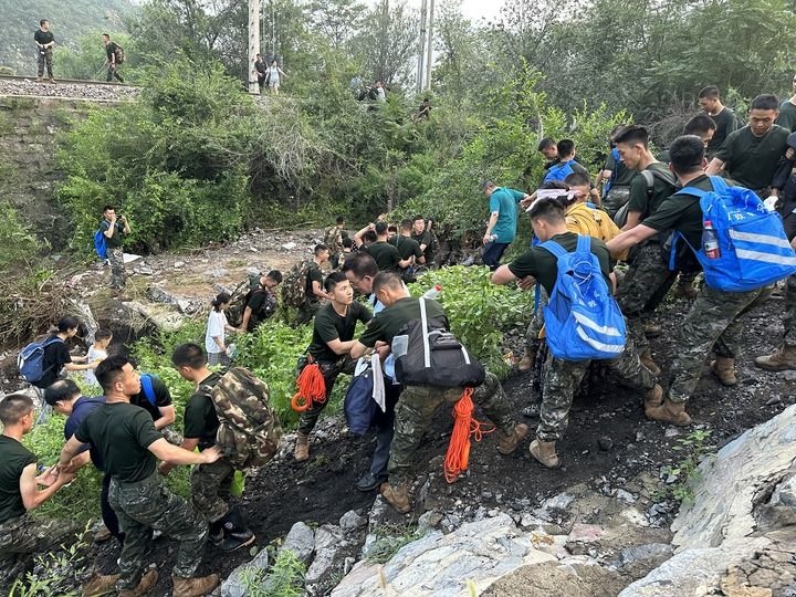 8月2日，Z180次受困列車(chē)的旅客在武警北京總隊(duì)機(jī)動(dòng)第三支隊(duì)官兵的幫助下徒步前往轉(zhuǎn)運(yùn)客車(chē)（手機(jī)照片）。新華社記者 王艷剛 攝