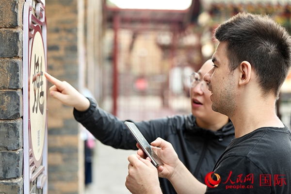 選手安德烈（俄羅斯）在老師指導(dǎo)下學(xué)習(xí)墻壁上張貼的生僻字。人民網(wǎng) 盧鵬宇攝