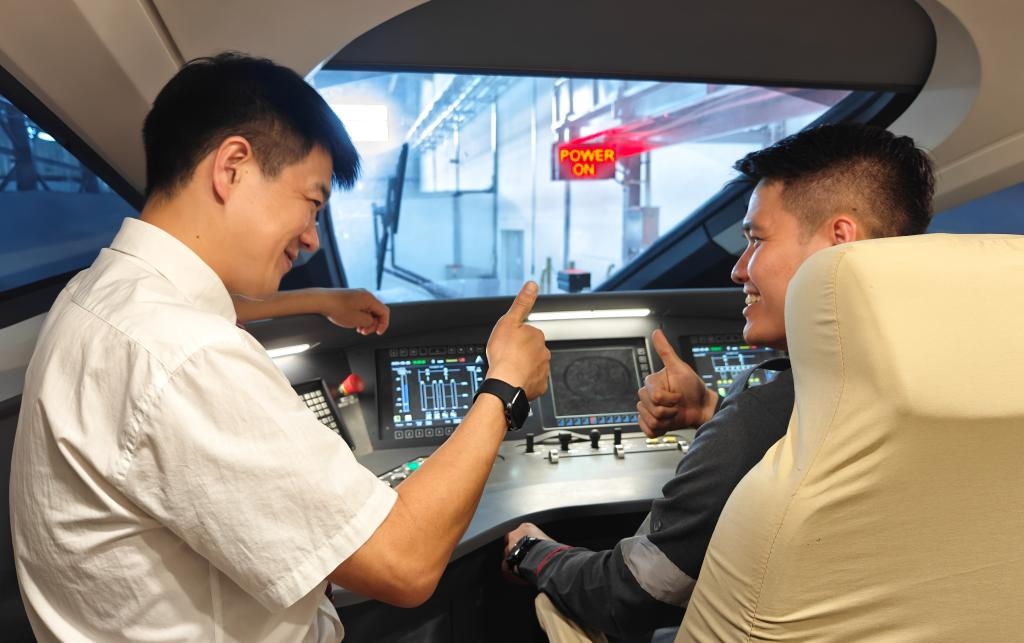 8月25日，在印度尼西亞萬隆的雅萬高鐵德卡魯爾動車所內(nèi)，中國師傅穆振（左）在向印尼火車司機塞蒂亞萬講解動車組出庫前的上電作業(yè)。
