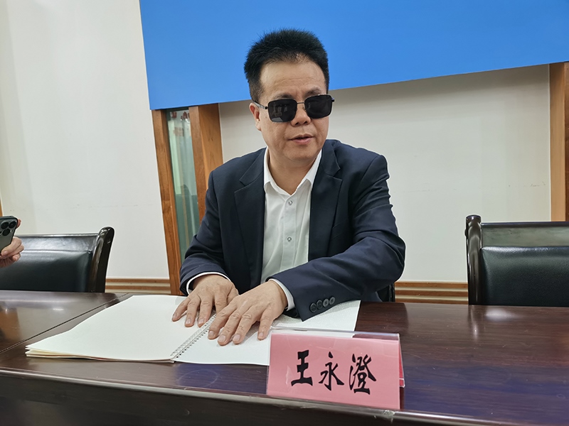 全國(guó)人大代表王永澄正在閱讀盲文版代表建議答復(fù)。本報(bào)記者 張 璁?dāng)z