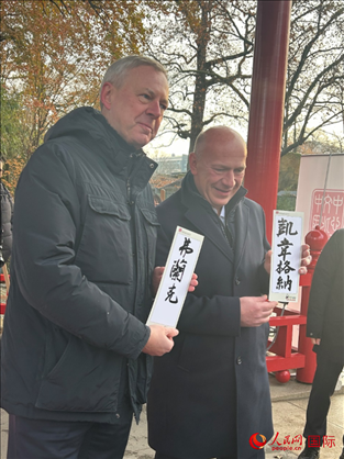 柏林市長韋格納（右）、動物園監(jiān)事會主席布魯克曼（左）手持中國文化中心工作人員現(xiàn)場手書的中文名字。人民網(wǎng)記者 徐馨攝