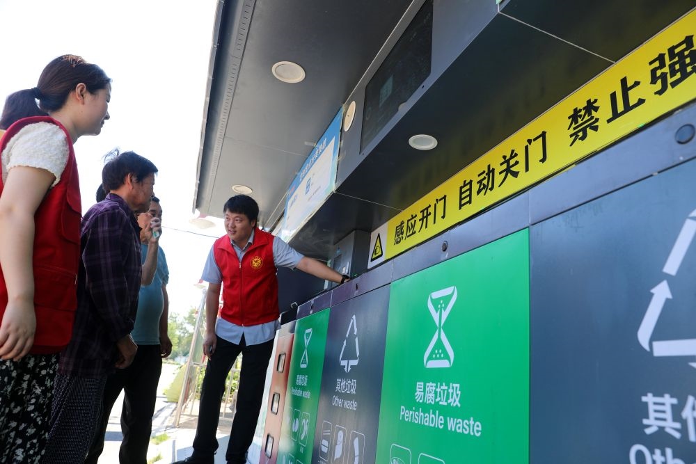 在安徽省合肥市長豐縣莊墓鎮(zhèn)棗林社區(qū)，志愿者指導(dǎo)居民使用智能垃圾分類回收設(shè)備（2023年9月1日攝）。新華社記者 曹力 攝
