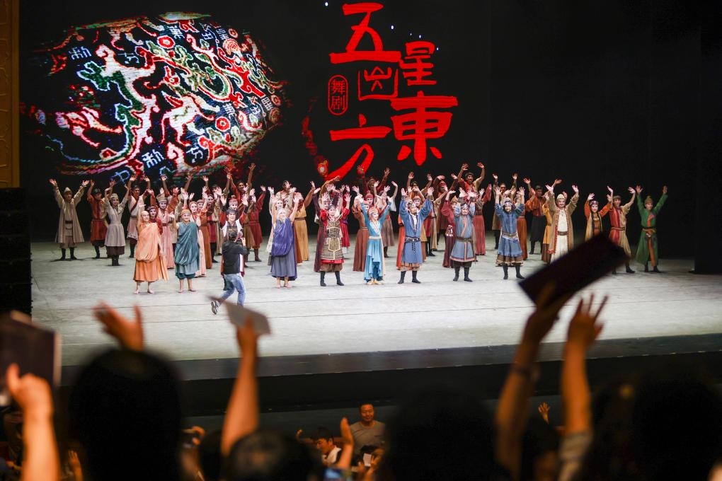 2023年7月31日，新疆和田地區(qū)新玉歌舞團(tuán)在烏魯木齊京劇院演出舞劇《五星出東方》后和觀眾互相揮手致意。這場演出是第六屆中國新疆國際民族舞蹈節(jié)的參演劇目之一，曾榮獲國家“文華獎(jiǎng)”等。新華社記者 郝昭 攝
