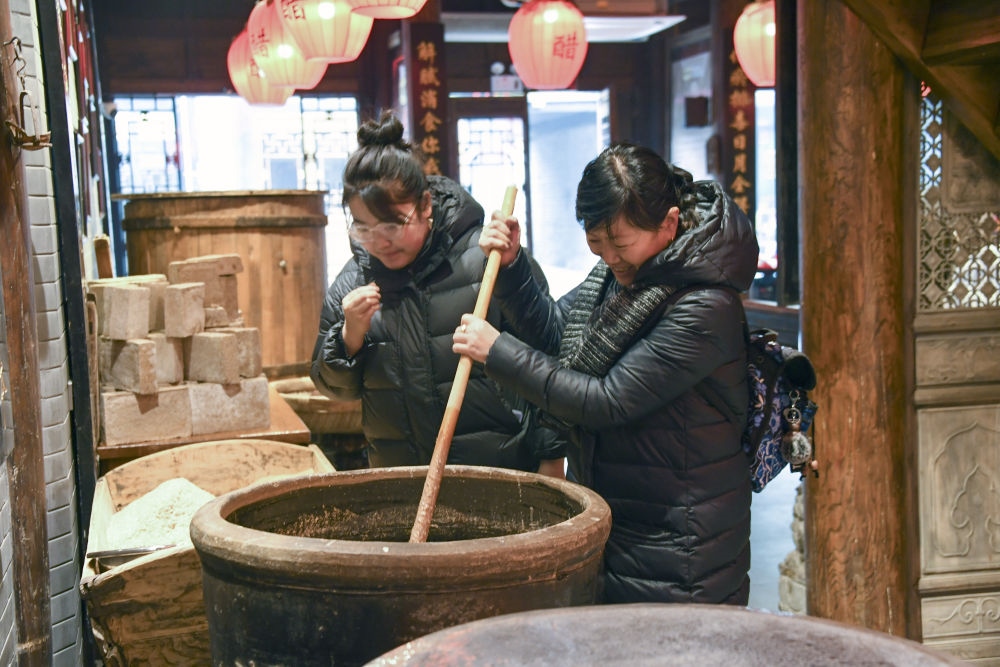 游客在平遙古城東湖老醋坊內(nèi)體驗(yàn)陳醋發(fā)酵打耙（2022年1月28日攝）。新華社發(fā)（梁生仁攝）