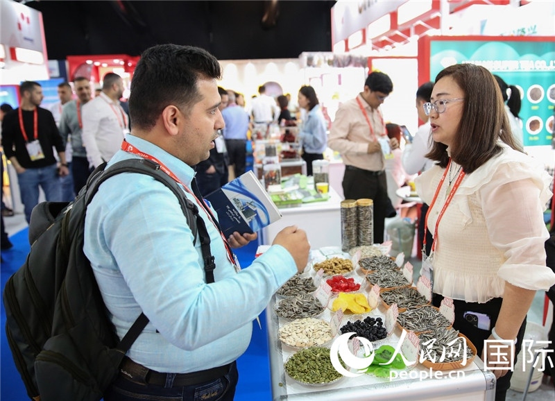 圖為一家中國干果參展企業(yè)代表與采購商洽談。人民網 塔里克·易卜拉欣攝