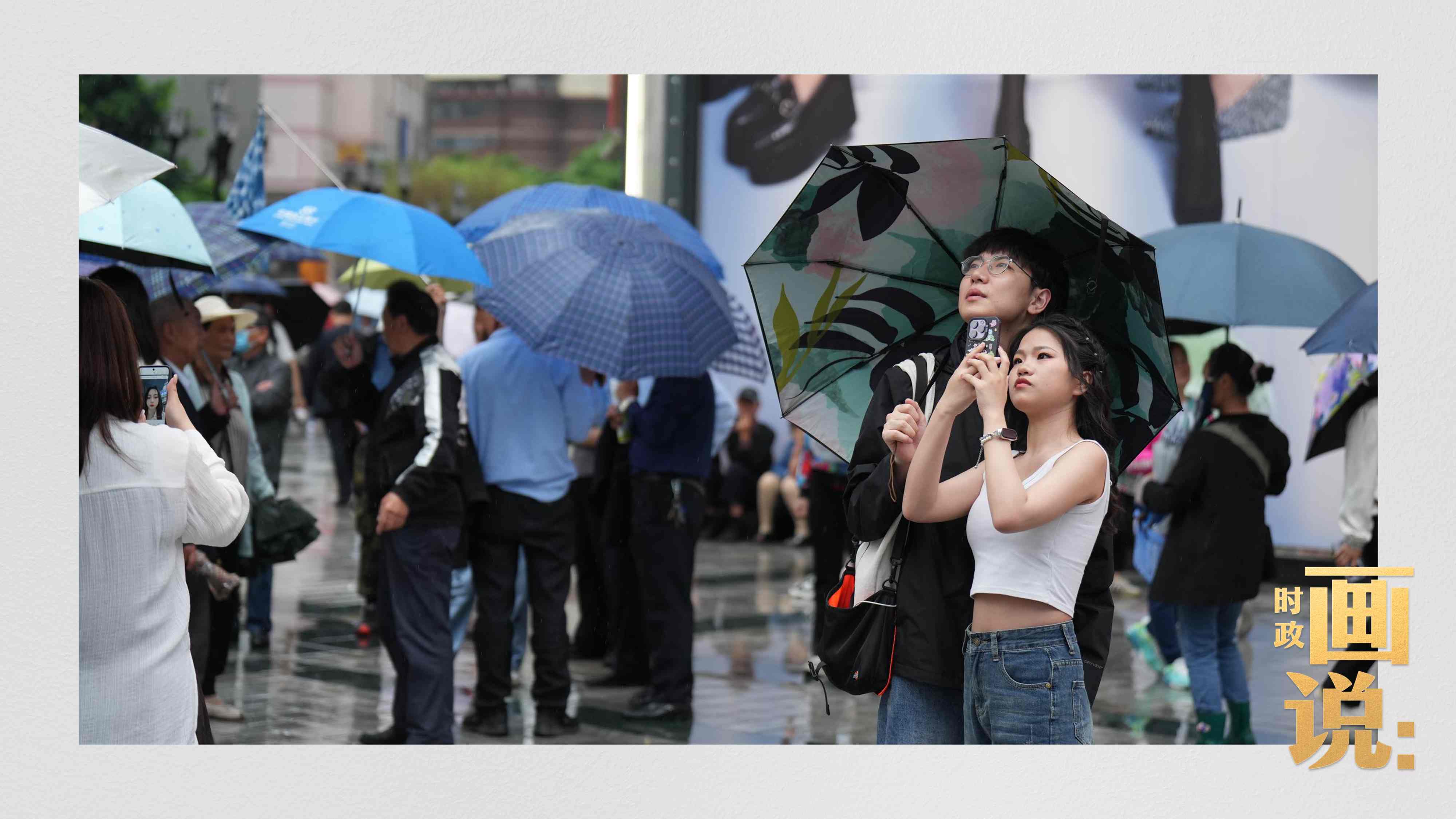 △細雨中的解放碑步行街，騎在父親肩膀的小女孩好奇張望。