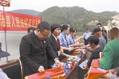 法院干警及相關(guān)部門工作人員對群眾進(jìn)行生態(tài)環(huán)境保護(hù)普法教育。