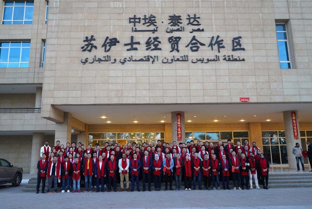 2024年2月11日，在位于埃及蘇伊士省的中?！ぬ┻_(dá)蘇伊士經(jīng)貿(mào)合作區(qū)，中埃員工在合作區(qū)辦公大樓前合影拜年。新華社發(fā)（泰達(dá)合作區(qū)供圖）