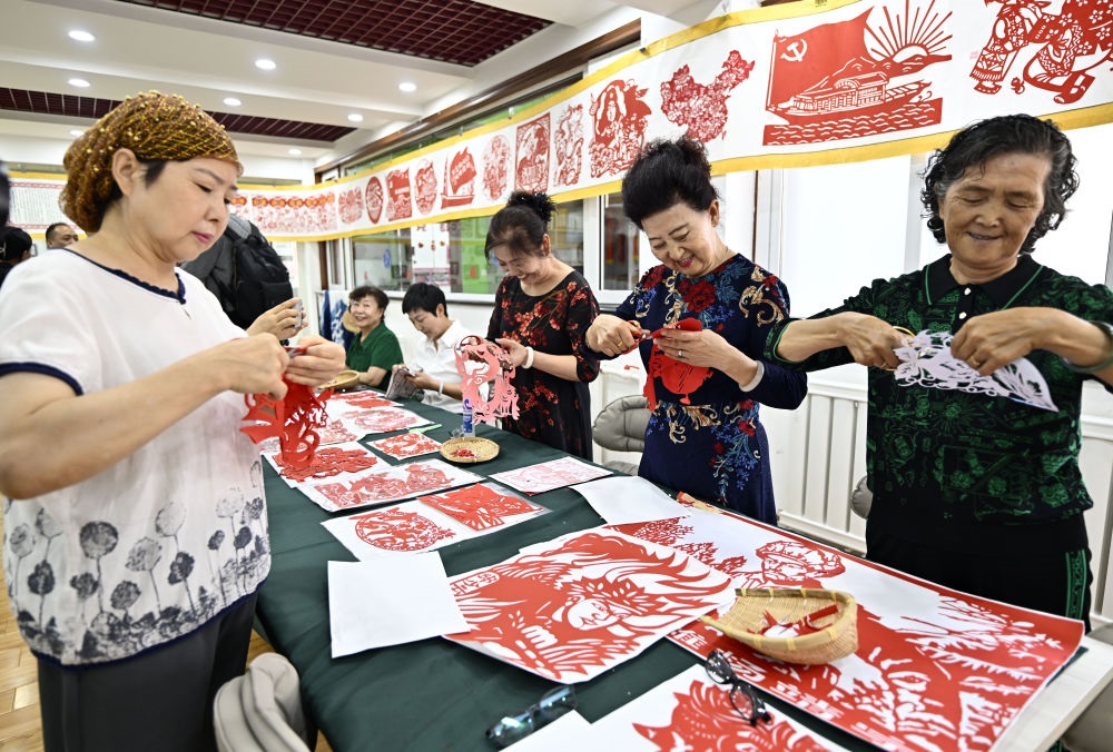 6月19日，長城花園社區(qū)居民在社區(qū)“才藝堂”制作剪紙。