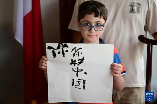 7月4日，在馬耳他桑塔露琪亞市的中國古典園林“靜園”，一名男孩展示他的書法作品。新華社發(fā)（喬納森·博格 攝）