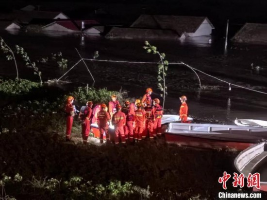  7月6日凌晨3時，在湖南岳陽華容縣團洲垸洞庭湖一線堤防，救援人員剛剛完成一次救援任務，遠處是被淹的民房。中新社記者 白祖偕 攝
