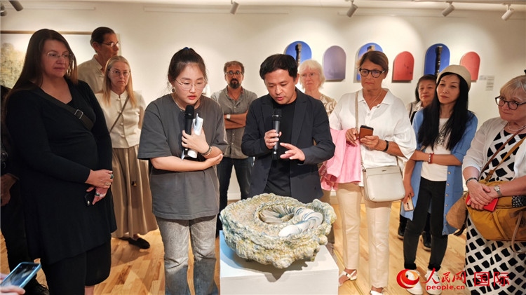參展人、景德鎮(zhèn)陶瓷大學(xué)設(shè)計(jì)藝術(shù)學(xué)院副院長余劍峰（中）向來賓介紹參展作品。人民網(wǎng)記者 殷淼攝