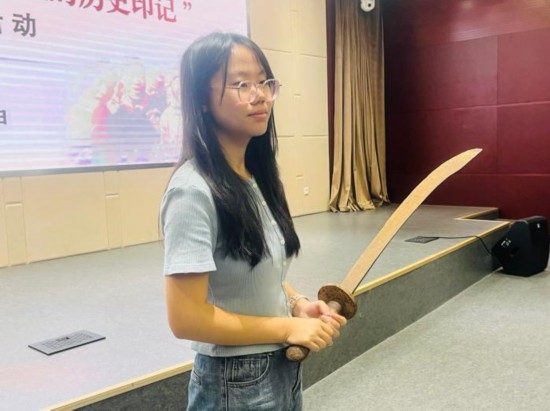 圖為南開大學(xué)社會(huì)實(shí)踐隊(duì)學(xué)生代表呼月紅在學(xué)術(shù)交流活動(dòng)現(xiàn)場(chǎng)，展示河間調(diào)研行中獲贈(zèng)的一戰(zhàn)華工蔡世春曾使用過的一把大刀。林卓瑋 攝