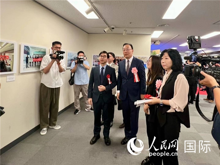 中國國際航空日韓地區(qū)支社支社長馮力為中國駐日本大使館臨時代辦施泳等嘉賓介紹展出圖片。人民網(wǎng) 許可攝