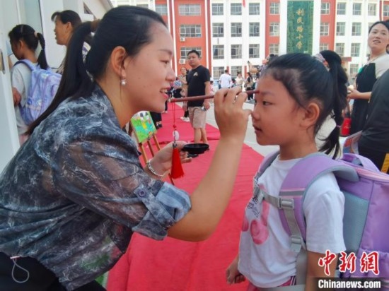 圖為衡水市利民路小學(xué)，老師為學(xué)生點(diǎn)朱砂痣，寓意開啟智慧。張松 攝