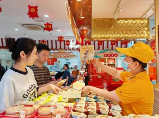 北京稻香村一家門(mén)店內(nèi)，售貨員向顧客展示新上市的月餅禮盒。（受訪者供圖）