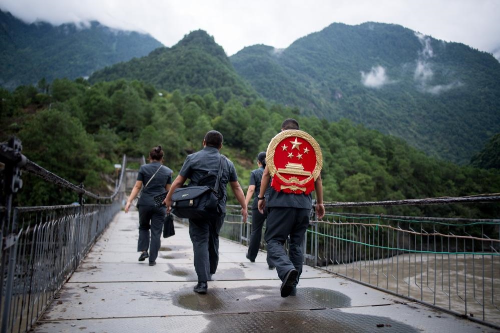 云南省怒江傈僳族自治州貢山縣人民法院法官鄧興背著國徽與同事們跨過怒江（2019年8月30日攝）。怒江高山峽谷眾多，交通不便，為方便群眾、更好地開展法律服務(wù)，背著國徽攀高山、過索橋、躲落石、鉆老林……成為鄧興法官的工作常態(tài)。新華社記者 江文耀 攝