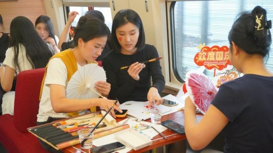 10月1日，旅客們在G1634次列車上給油紙傘作畫。新華社記者周義 攝