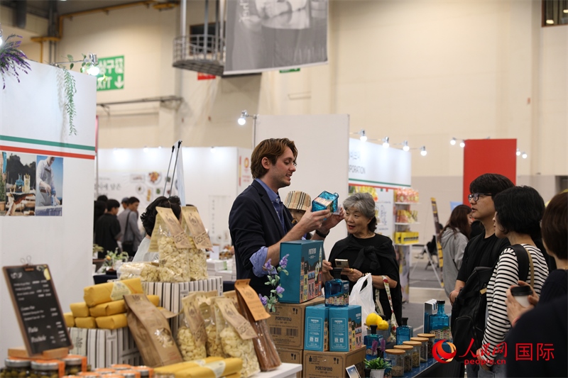 當(dāng)?shù)貢r間10月5日，在第21屆釜山國際美食博覽會上，意大利展商向參觀者們介紹的意大利食品。人民網(wǎng)記者 莽九晨攝