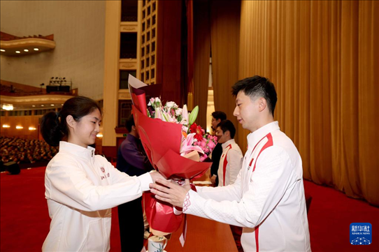 11月15日，一名學(xué)生代表在報告會上向乒乓球運動員馬龍（右）獻(xiàn)花。新華社記者 李明 攝