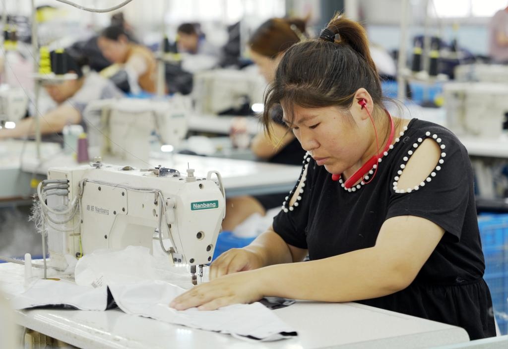 5月20日，村民在李寨村服裝加工廠內(nèi)忙碌。河南省周口市沈丘縣馮營鎮(zhèn)李寨村地處豫東平原。近年來，乘著脫貧攻堅與鄉(xiāng)村振興政策的東風(fēng)，李寨村積極探索產(chǎn)業(yè)發(fā)展模式，通過“龍頭企業(yè)+村集體經(jīng)濟(jì)+農(nóng)戶”的方式，逐漸發(fā)展形成肉牛養(yǎng)殖、設(shè)施農(nóng)業(yè)、服裝加工、康養(yǎng)民宿等產(chǎn)業(yè)，以產(chǎn)業(yè)振興助力鄉(xiāng)村振興。新華社記者 李嘉南 攝