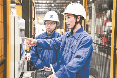 在廣西柳工機(jī)械股份有限公司生產(chǎn)車間內(nèi)，一名高級(jí)技師（右）給徒弟講解數(shù)控設(shè)備操作細(xì)節(jié)。新華社記者 曹祎銘攝