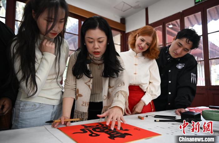 1月20日，西泠印社社員李硯（左二）為外籍留學(xué)生講述蛇年福字貼創(chuàng)作靈感。當(dāng)日，來(lái)自巴西、馬來(lái)西亞、加納、哈薩克斯坦的外籍留學(xué)生在浙江杭州西泠印社體驗(yàn)福貼、春聯(lián)和篆刻，感受古老的中國(guó)傳統(tǒng)文化。中新社記者 王剛 攝