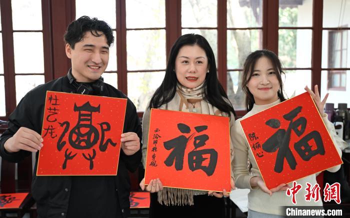 1月20日，外籍留學(xué)生和西泠印社社員李硯(中)展示各自創(chuàng)作的福貼。當(dāng)日，來(lái)自巴西、馬來(lái)西亞、加納、哈薩克斯坦的外籍留學(xué)生在浙江杭州西泠印社體驗(yàn)福貼、春聯(lián)和篆刻，感受古老的中國(guó)傳統(tǒng)文化。中新社記者 王剛 攝