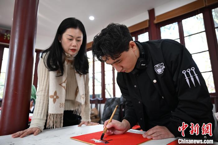 1月20日，外籍留學(xué)生在西泠印社社員李硯指導(dǎo)下寫(xiě)福。當(dāng)日，來(lái)自巴西、馬來(lái)西亞、加納、哈薩克斯坦的外籍留學(xué)生在浙江杭州西泠印社體驗(yàn)福貼、春聯(lián)和篆刻，感受古老的中國(guó)傳統(tǒng)文化。中新社記者 王剛 攝