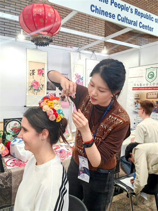 展覽正值羅馬尼亞迎春花節(jié)，國(guó)際中文教師志愿者潘婧穎向游客們介紹了國(guó)家非物質(zhì)文化遺產(chǎn)——福建泉州的簪花文化。布加勒斯特大學(xué)孔子學(xué)院供圖。